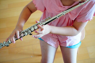 椅子に座ってフルートの練習をしている小学5年生の女の子の手元。