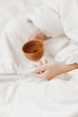 Person in bed with tea and water, another person holding tea and water