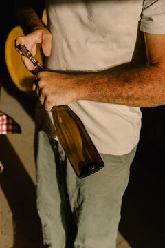 Close up of a man using a corkscrew to open a bottle of wine