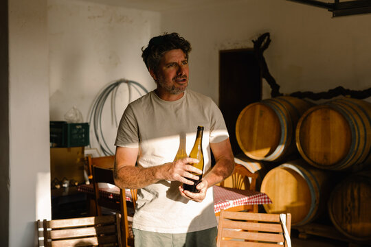 Proprietor of a small winery holds a bottle of artisanal wine