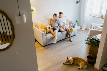 Happy family couple with a cute corgi dog relaxing in a living room
