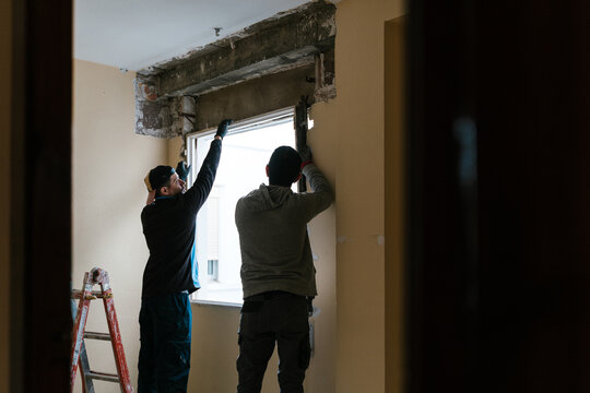 Focused workmen fixing glass window in apartment