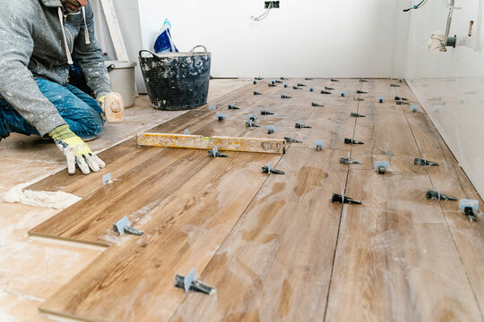 Anonymous tile layer installing modern wood flooring during renovation