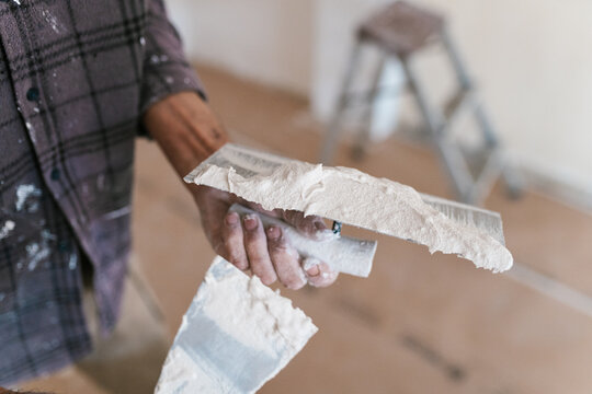 Crop carpenter holding plaster with Trowel