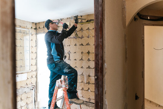 Focused bricklayer working on shabby brick wall