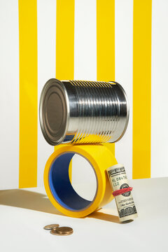 Stack of can, tape, and money against yellow striped background.