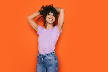 Joyful Moroccan woman posing confidently against orange background