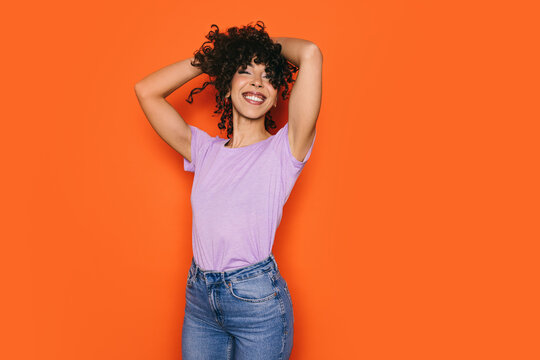 Joyful Moroccan woman posing confidently against orange background