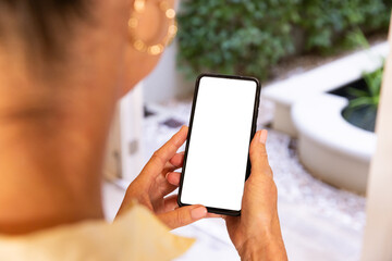 Holding smartphone with blank screen, woman standing in modern home environment, copy space