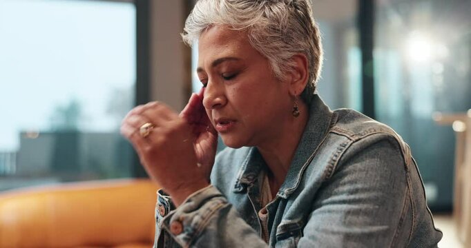Mature woman, headache and pain in living room with stress, hurt and brain aneurysm in modern home. Emergency, tension and female person on sofa with migraine, condition and anxiety in lounge