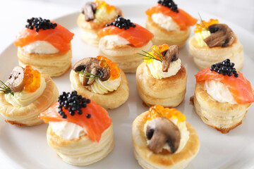Different delicious puff pastry snacks on plate, closeup