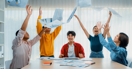 Excited and happy startup company employee celebrate and throw paper in the air after make...