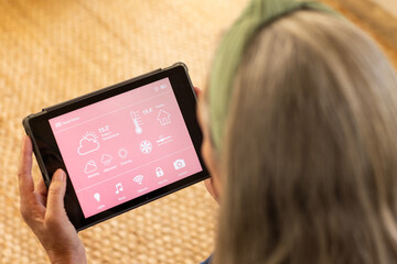 Using tablet, woman managing smart home settings and checking weather forecast
