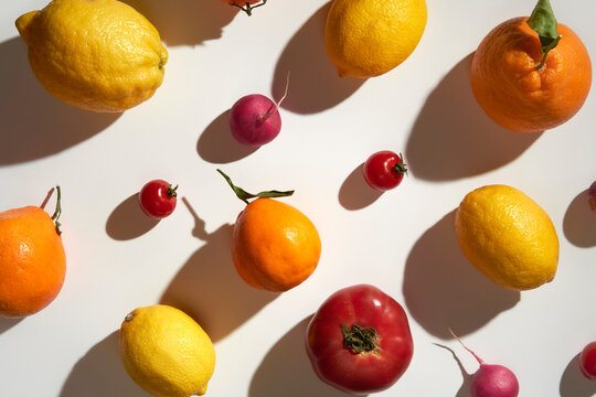 Fruit and vegetables making pattern on white background under sunlight
