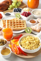Tasty breakfast. Scrambled eggs in bowl, bell pepper, honey and other food on light table, closeup