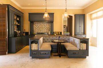 Modern kitchen with built-in seating area and pendant lights, cozy and inviting, copy space