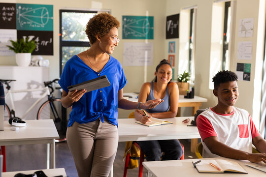 In high school, teacher using tablet while engaging with students in classroom