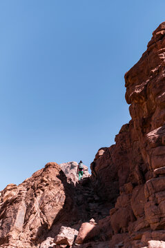 Hiker hiking rocky trail in desert mountain in summer