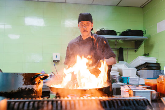 Chef Handling Ingredients Over High Flames
