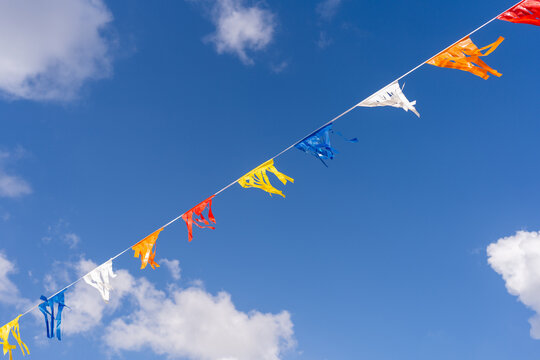 Colorful Flags Against Blue Sky With Clouds.