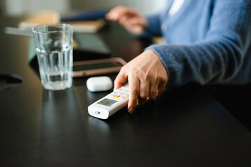 A woman controls the air conditioner using a remote control