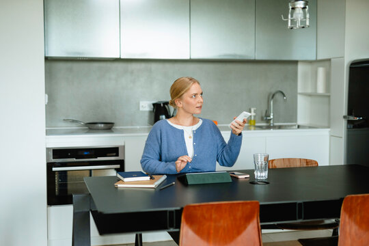 A woman controls the air conditioner using a remote control