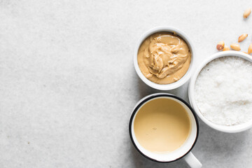 Overhead view of mise en place of ingredients for making peanut butter fudge, top view of peanut butter sugar and milk on a marble countertop, process of making peanut butter fudge