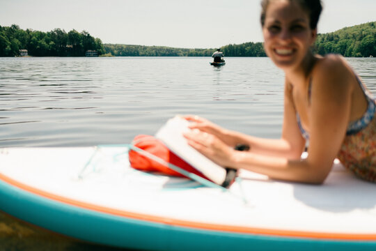 young woman reading. book on paddle board 