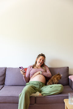 Pregnant woman laughing at home