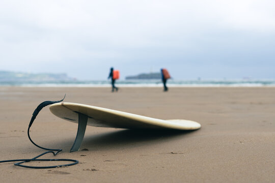 Hikers and a surfboard, on a beach, Somo, Spain. 
