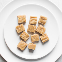 Overhead view of sliced peanut butter fudge on a white plate, top view of soft peanut fudge squares on a white ceramic plate