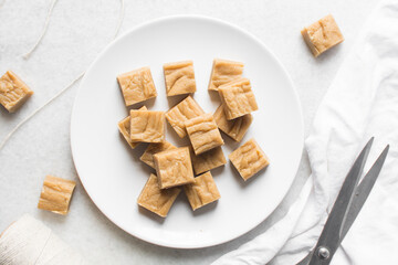 Overhead view of sliced peanut butter fudge on a white plate, top view of soft peanut fudge squares on a white ceramic plate