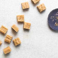 Overhead view of peanut butter fudge on a white marble tray, top view of soft peanut fudge squares on a white background