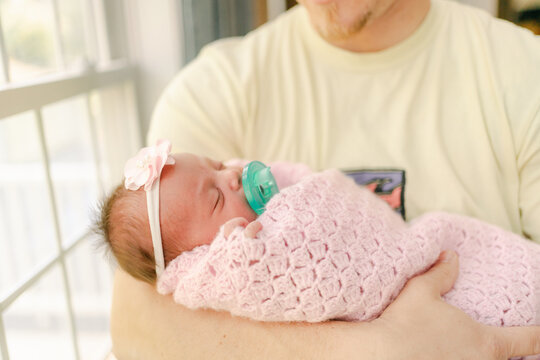 father holding newborn wapped in blanket 