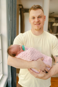 father holding newborn wapped in blanket 
