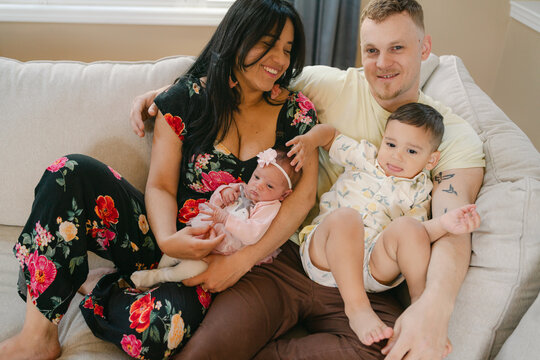 haopy portrait of multiracial family with their newborn snuggling 