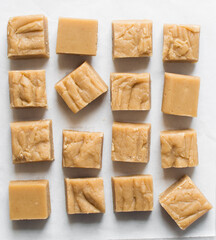 Overhead view of peanut butter fudge on a white marble tray, top view of soft peanut fudge squares on a white background