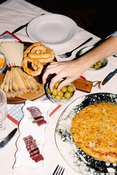 A hand taking an olive from a table set with traditional Spanish food