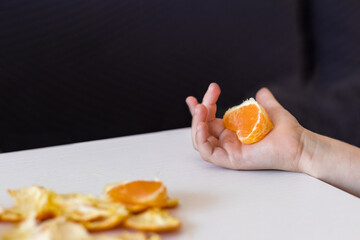 Children's hand hold a tangerine on the table