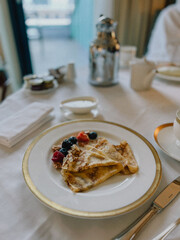 Delicious hotel breakfast with crepes, berries, cityscape backdrop