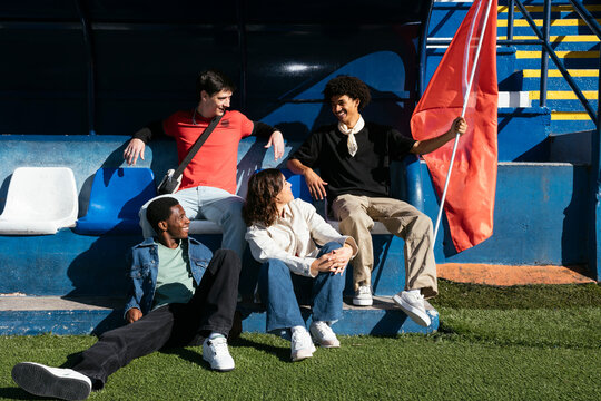 Group of fans having fun together while holding a red flag in stadium