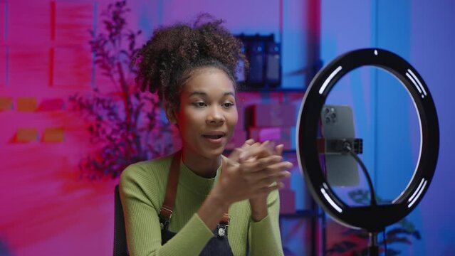 Woman clapping and showing thumbs up in a vibrant studio with professional lighting and colorful background. Perfect for content creators and influencers