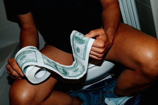 takes a piece of toilet paper patterned with 100 dollar bills