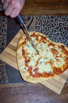 Cutting a heart-shaped pizza on wooden board 