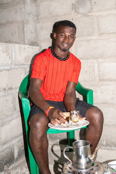 African man serving tea on home terrace