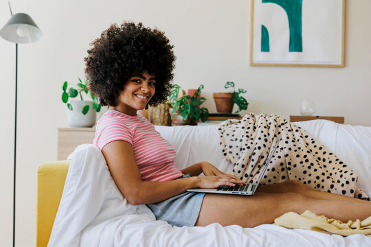 Cheerful woman enjoying time on laptop at home