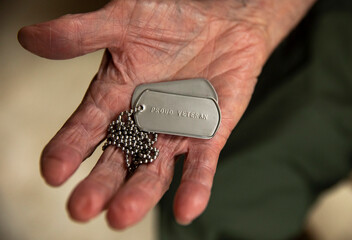 Military Dog tag veteran necklace  hand of senior 