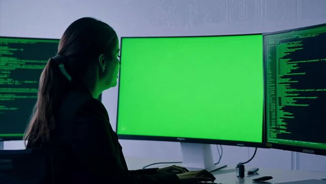 Young Indian female working at a computer that has a green screen for rotoscoping.  Tracking shot moving in close to subjet.