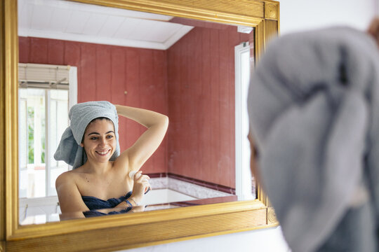 Woman With Towel On Head Using Deodorant Under Armpits.
