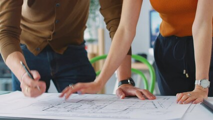 Close up of male and female architects in office standing at desk and working on plans - shot in slow motion